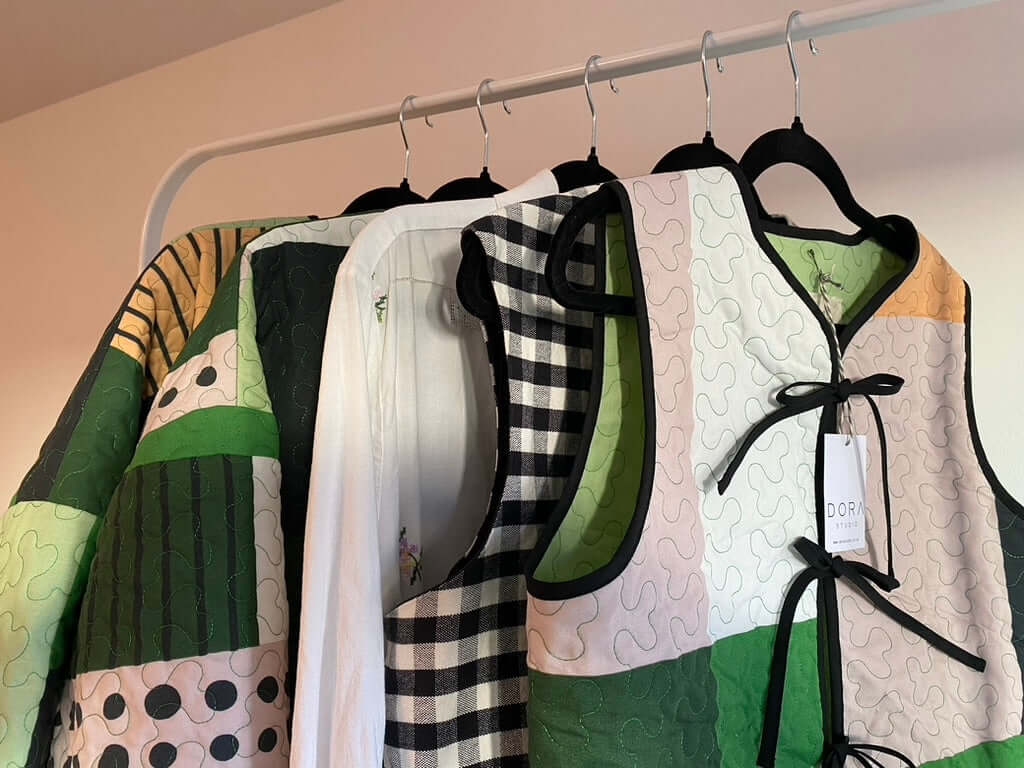 Patchwork quilted vest and quilted jacket hanging on a clothing rail.