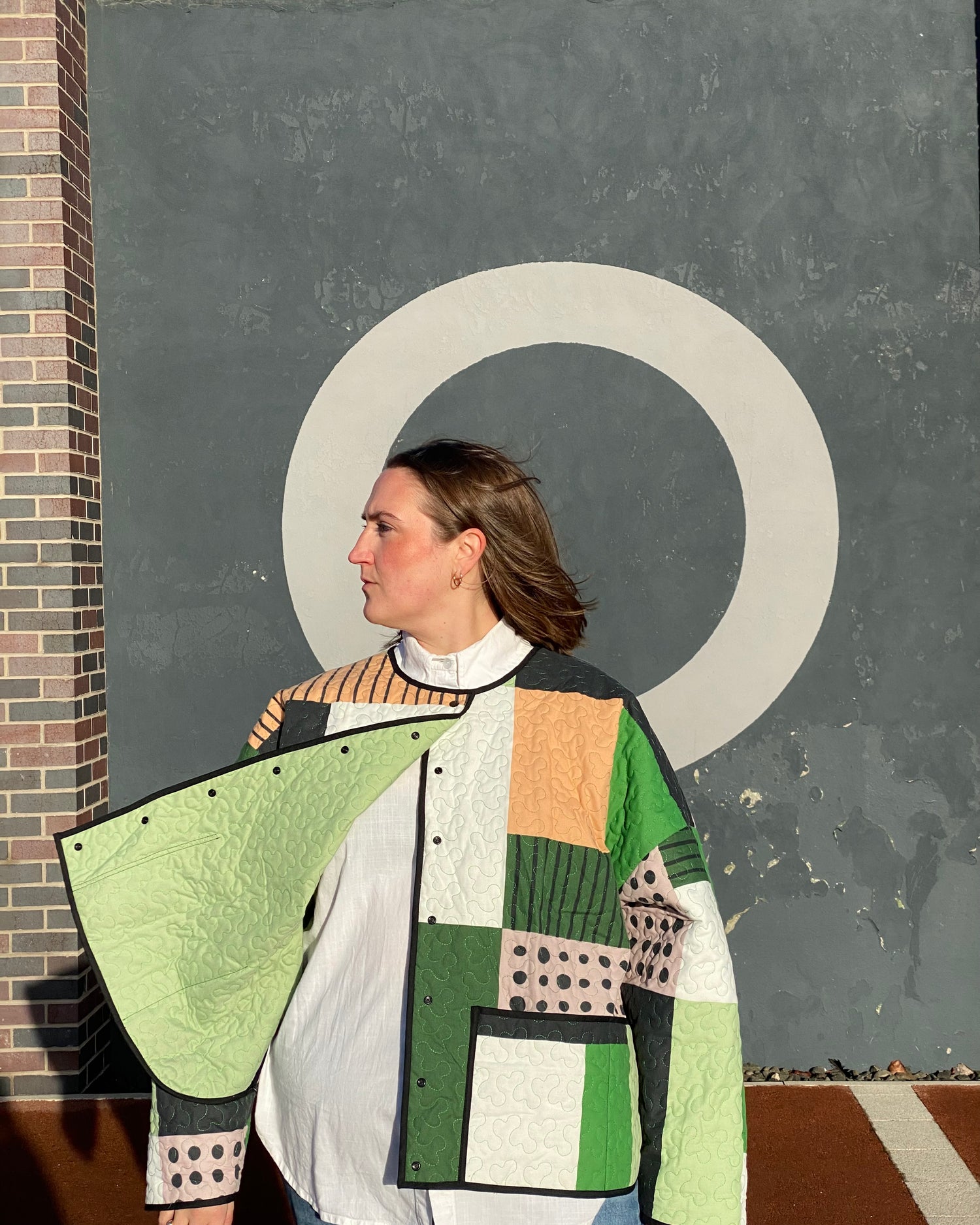 Close up of model wearing Christine Jacket, a quilted oversized fit with patchwork design, made from recycled blanket fabric.