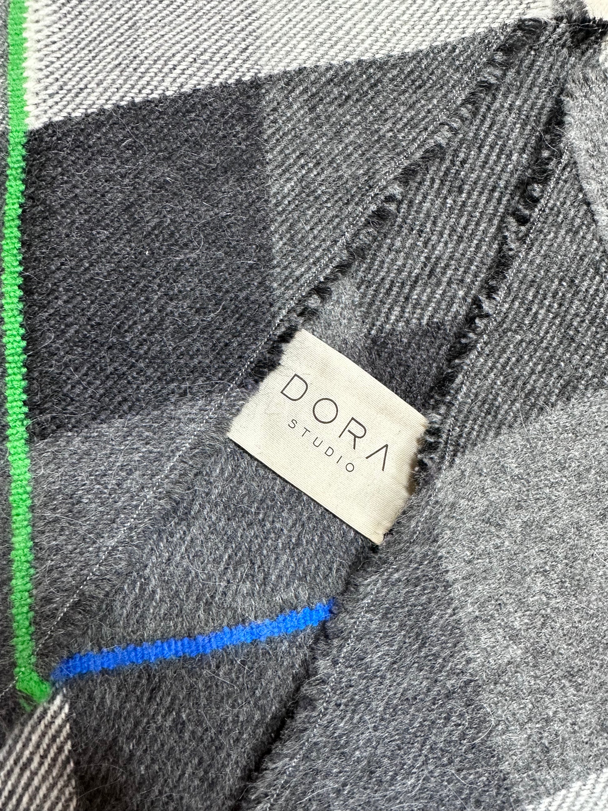 Close-up of a plaid fabric with a 'DORA studio' label.