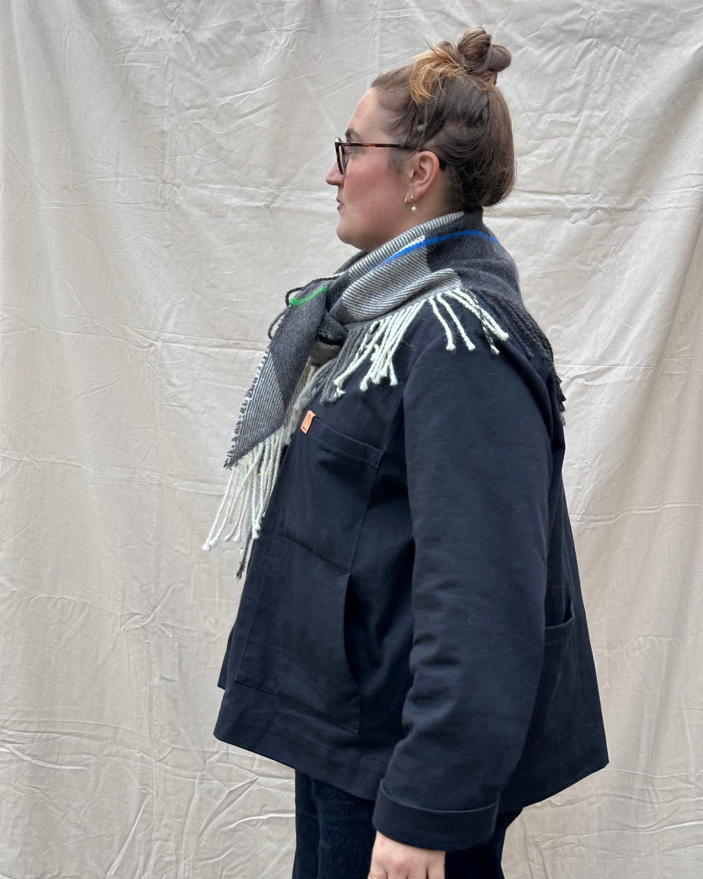 Person wearing a dark blue jacket and gray scarf against a plain background