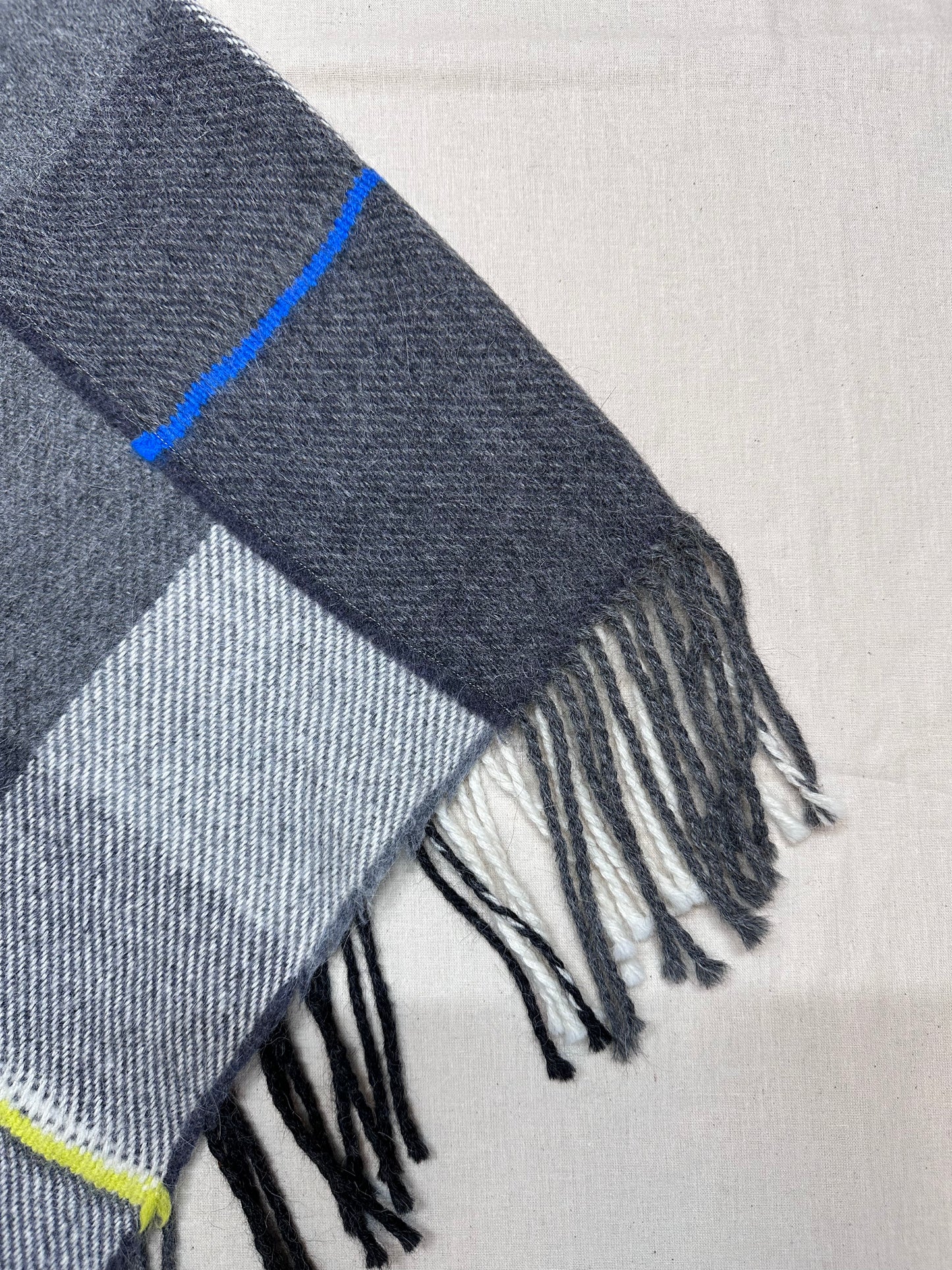 Gray checkered scarf with blue and yellow accents on a light gray background