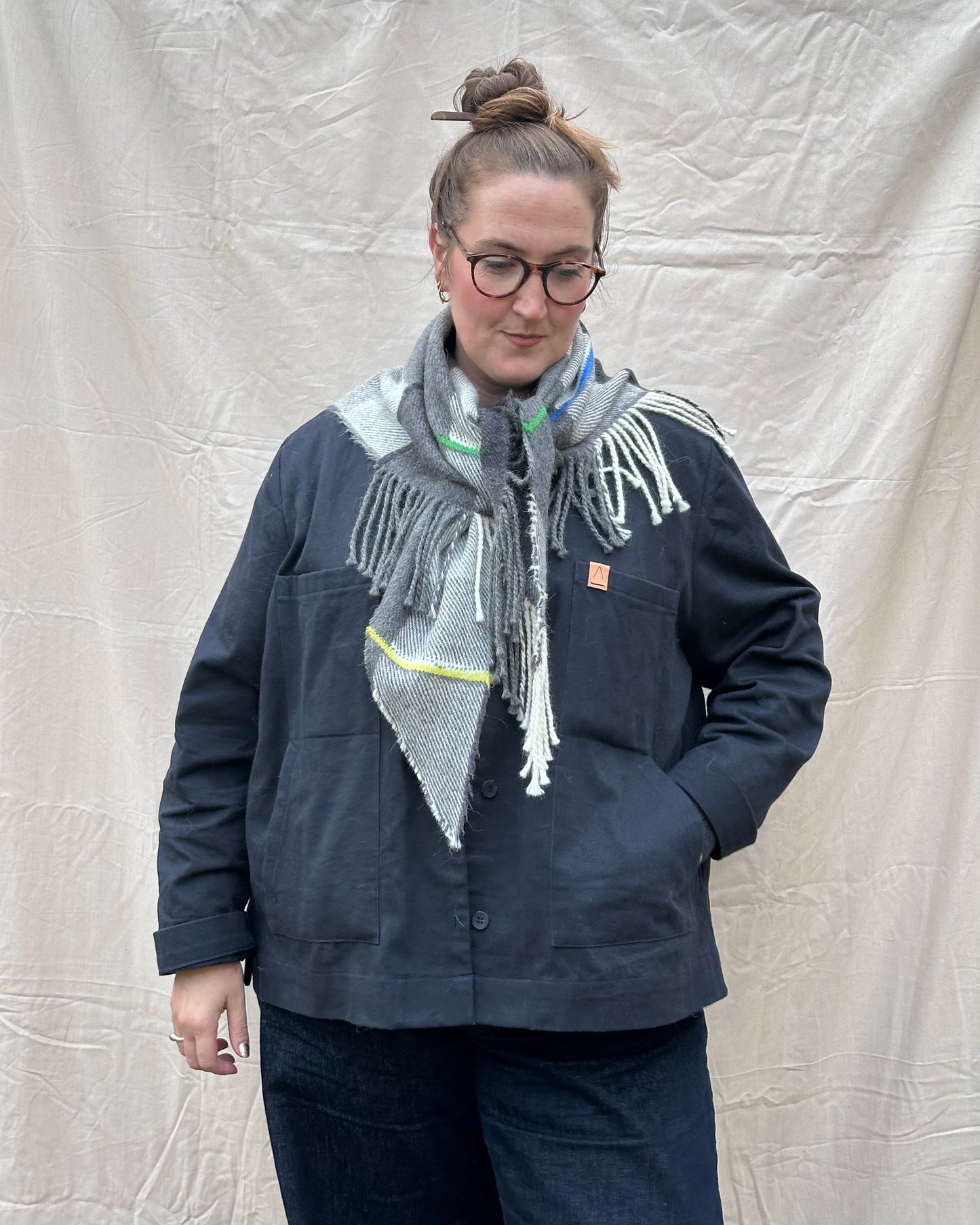 Person wearing a navy jacket and scarf against a plain background