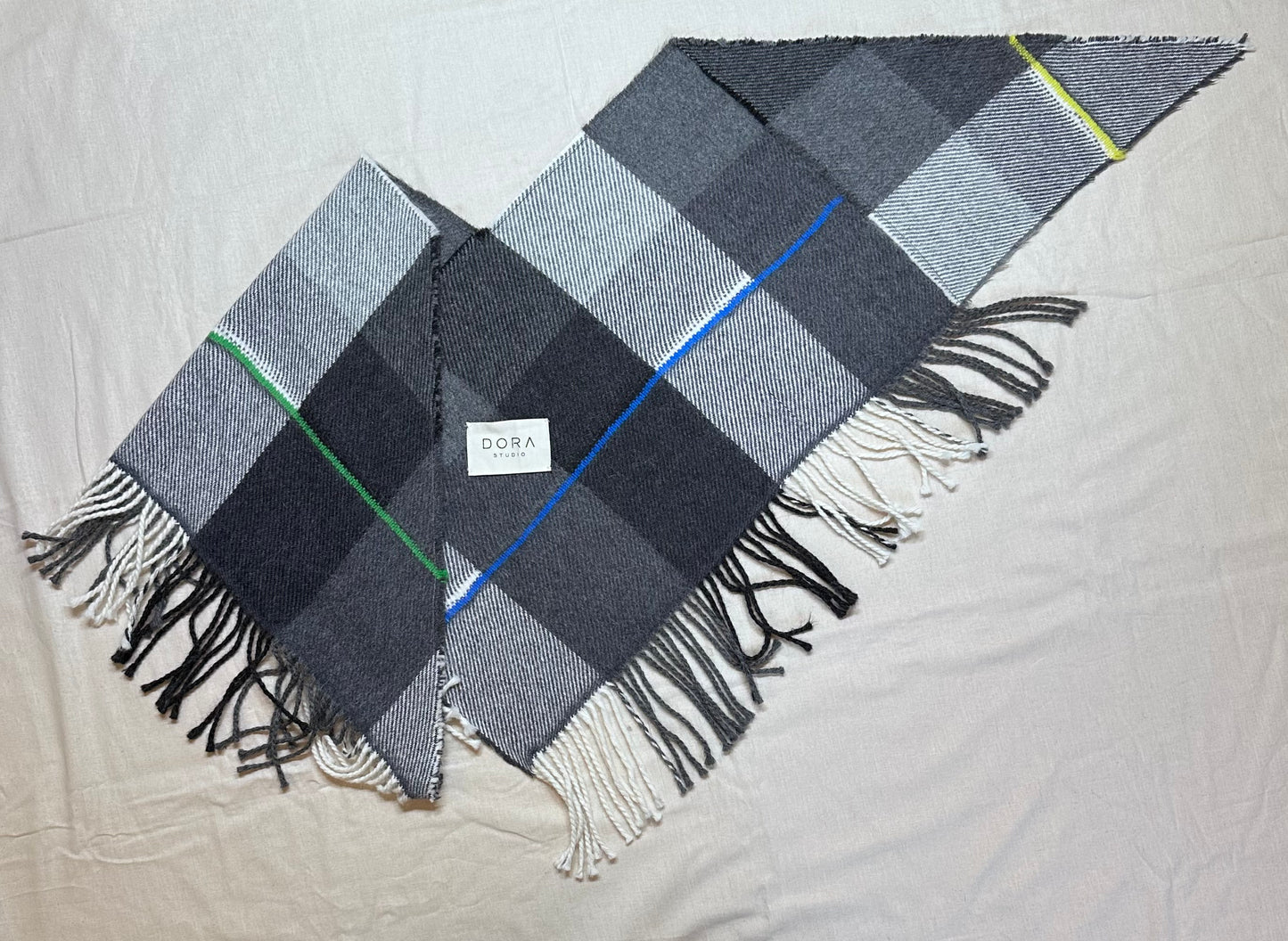 Plaid scarf with fringes on a light gray background